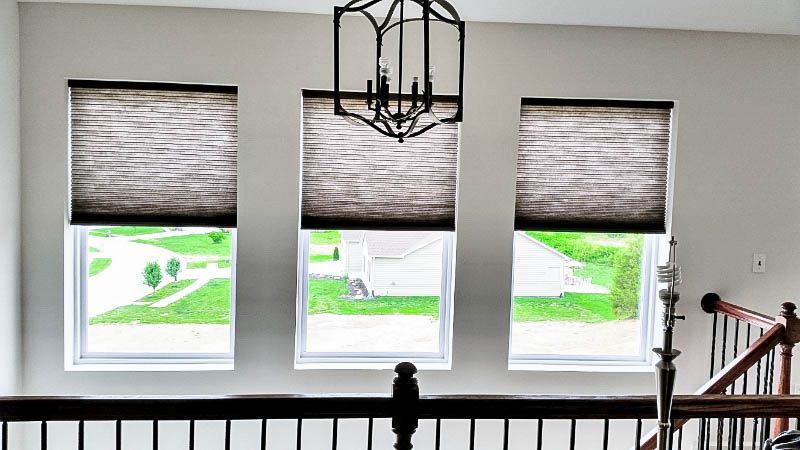 A staircase with three windows and a chandelier hanging from the ceiling.