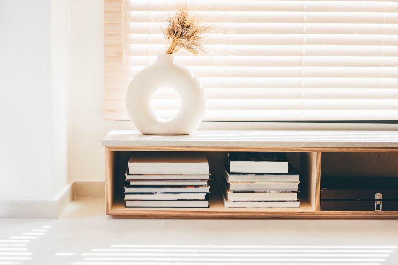 A shelf filled with books and a vase with a plant on it.