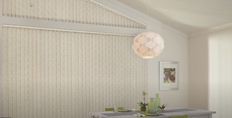 A dining room with a table and chairs and vertical blinds on the wall.