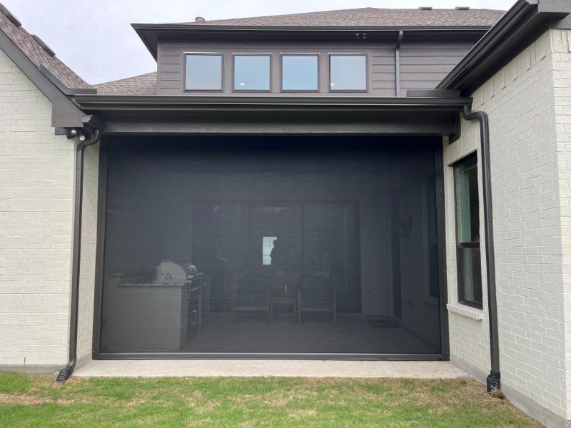 A patio section of a house is enclosed by an exterior patio shade. 