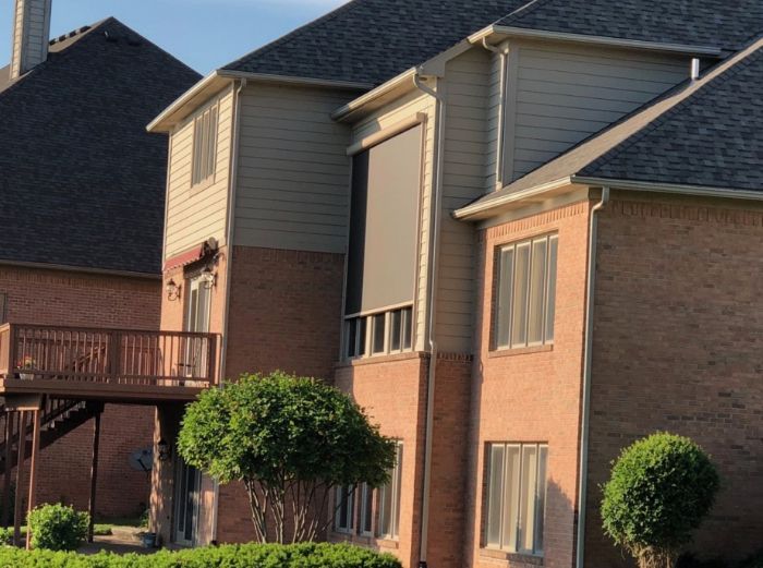 A brown multistory building has an exterior patio shade covering a large window. 