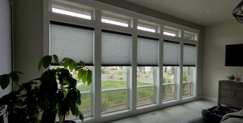 A bedroom with a wall of windows has cellular shades to regulate natural light. 