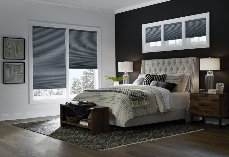 A bedroom with a bed , nightstand , and window honeycomb shades.