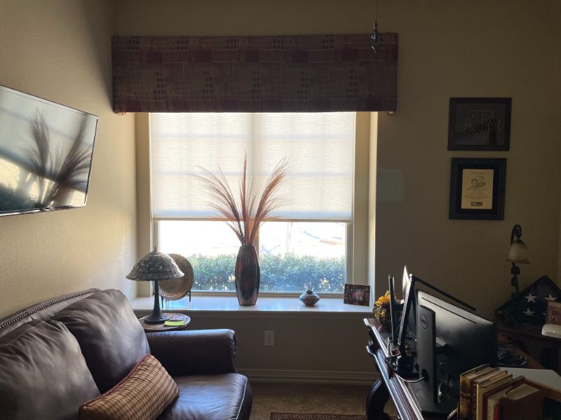 A living room with a couch a desk and a window