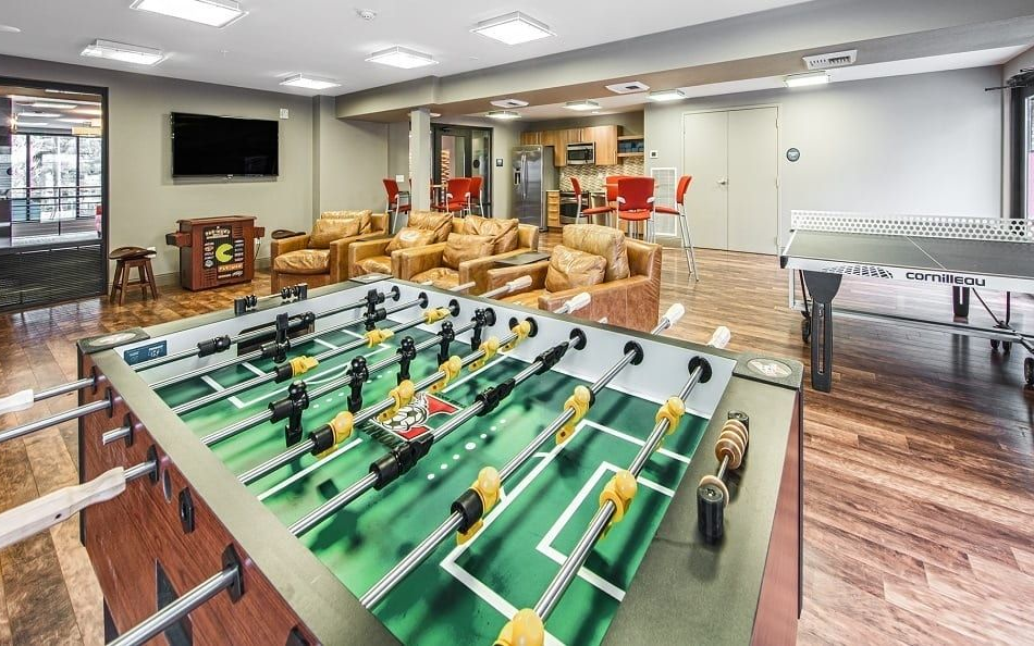 Foosball table in a lounge area, with couches, a ping pong table, and a TV.