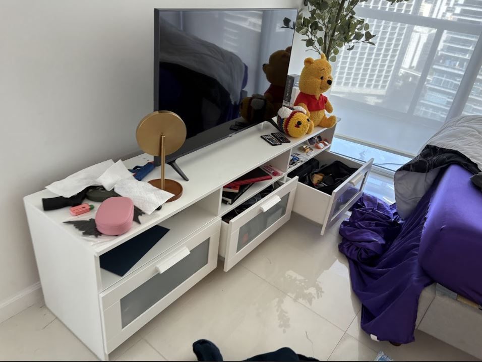 A messy room with a tv and a winnie the pooh teddy bear