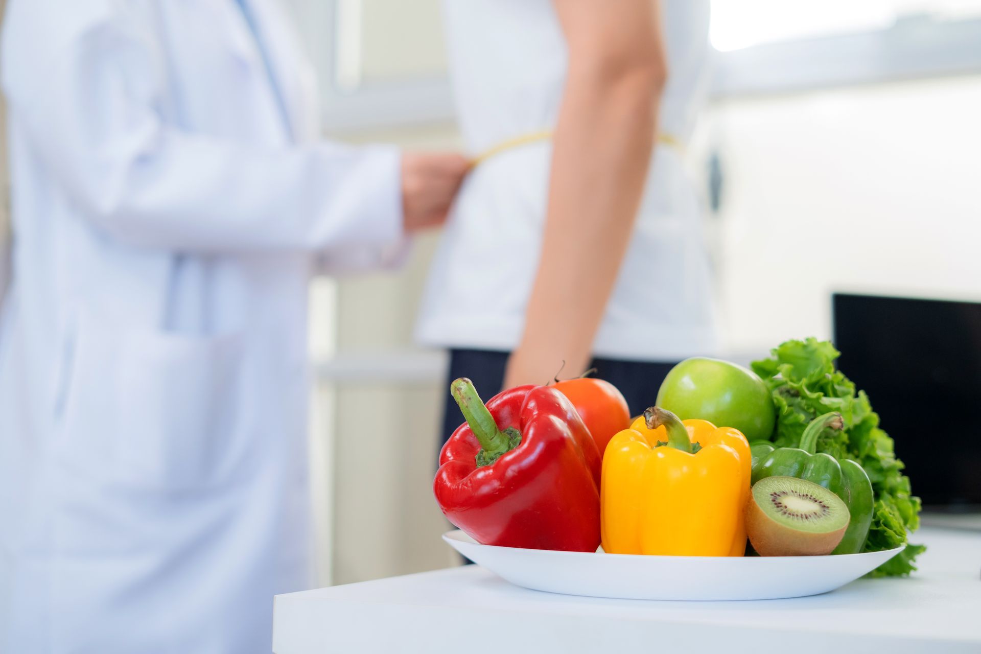 Nutritionist measuring patient waist with tape in clinic office.