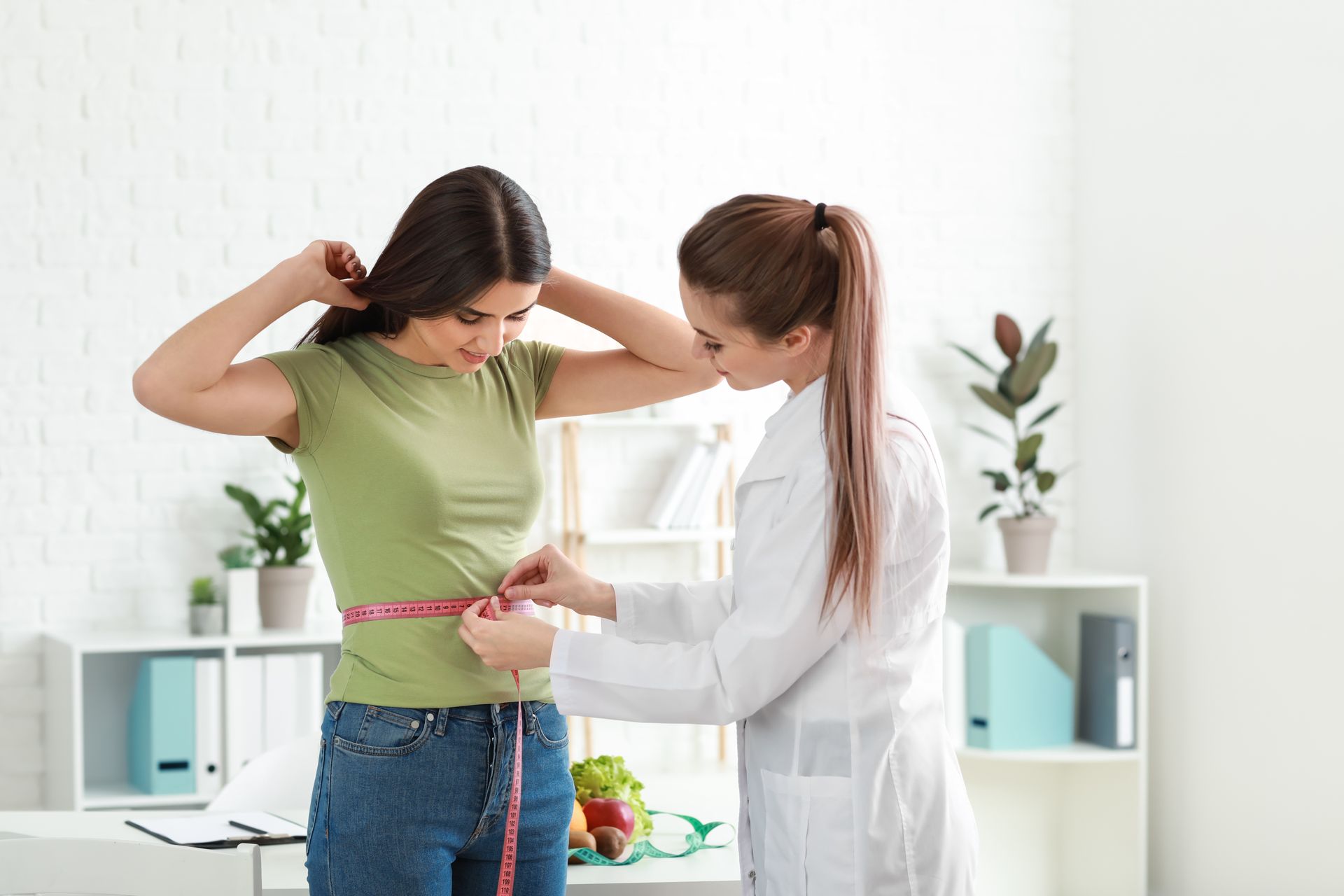 A doctor is measuring a patient’s waist.