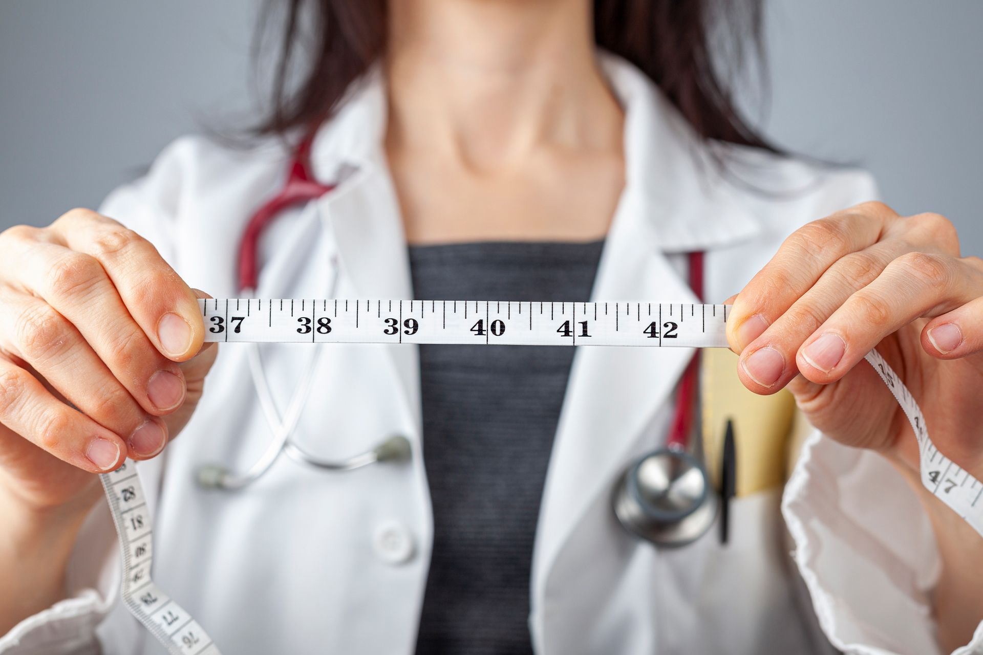 Doctor measuring waist, showcasing medical weight loss services for healthy abdominal health. Doctor measuring waist, showcasing medical weight loss services for healthy abdominal health.