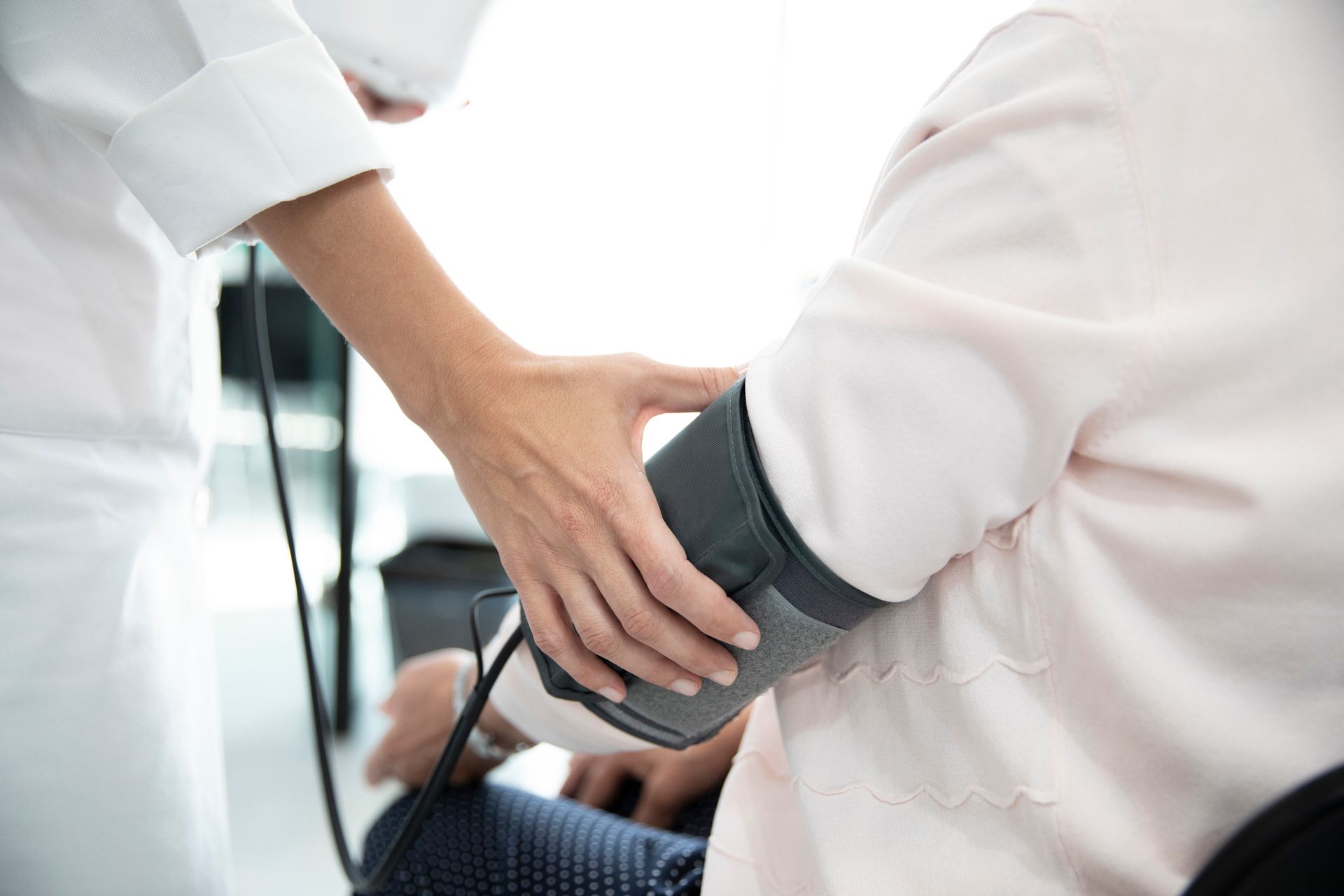 A healthcare worker taking an elderly patient's blood pressure with an arm cuff.