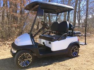 A white golf cart is parked on a dirt road.