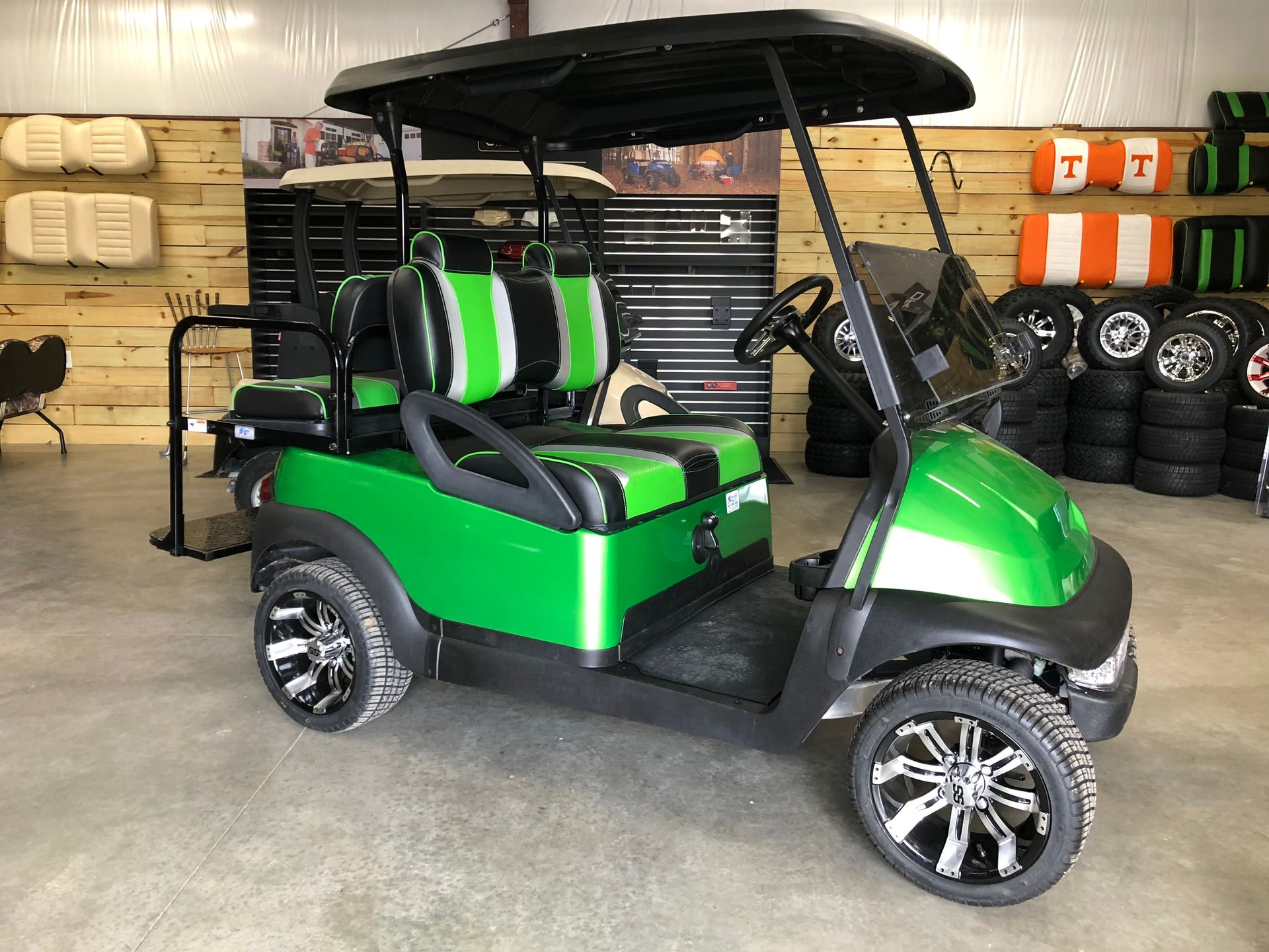 A green golf cart is parked in a garage.