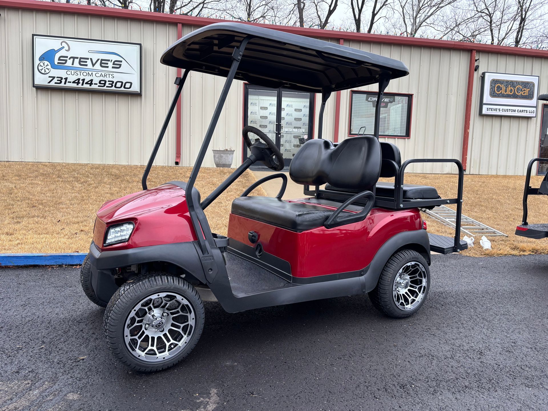 A black and gray golf cart is parked in front of a building.