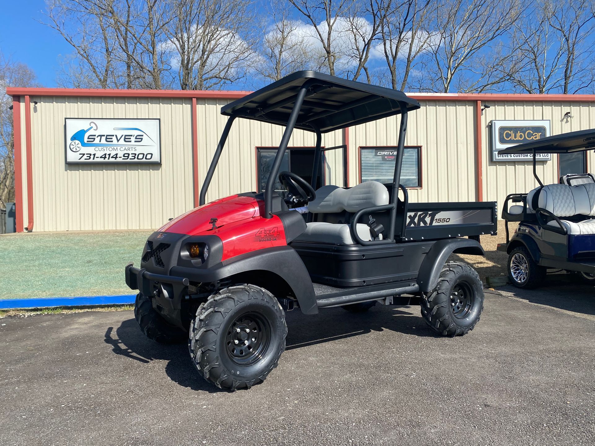A red golf cart is parked in front of a building.