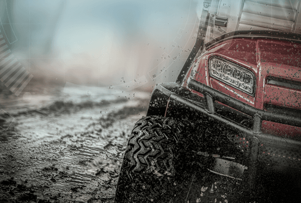Red ATV splashing through mud.