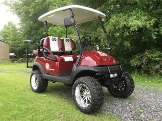 A red golf cart with white seats is parked in a grassy area.