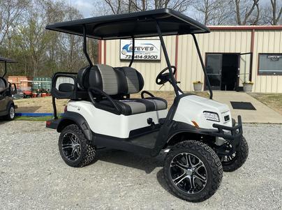 A white golf cart is parked in front of a building.