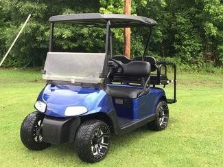 A blue golf cart is parked on a lush green field.