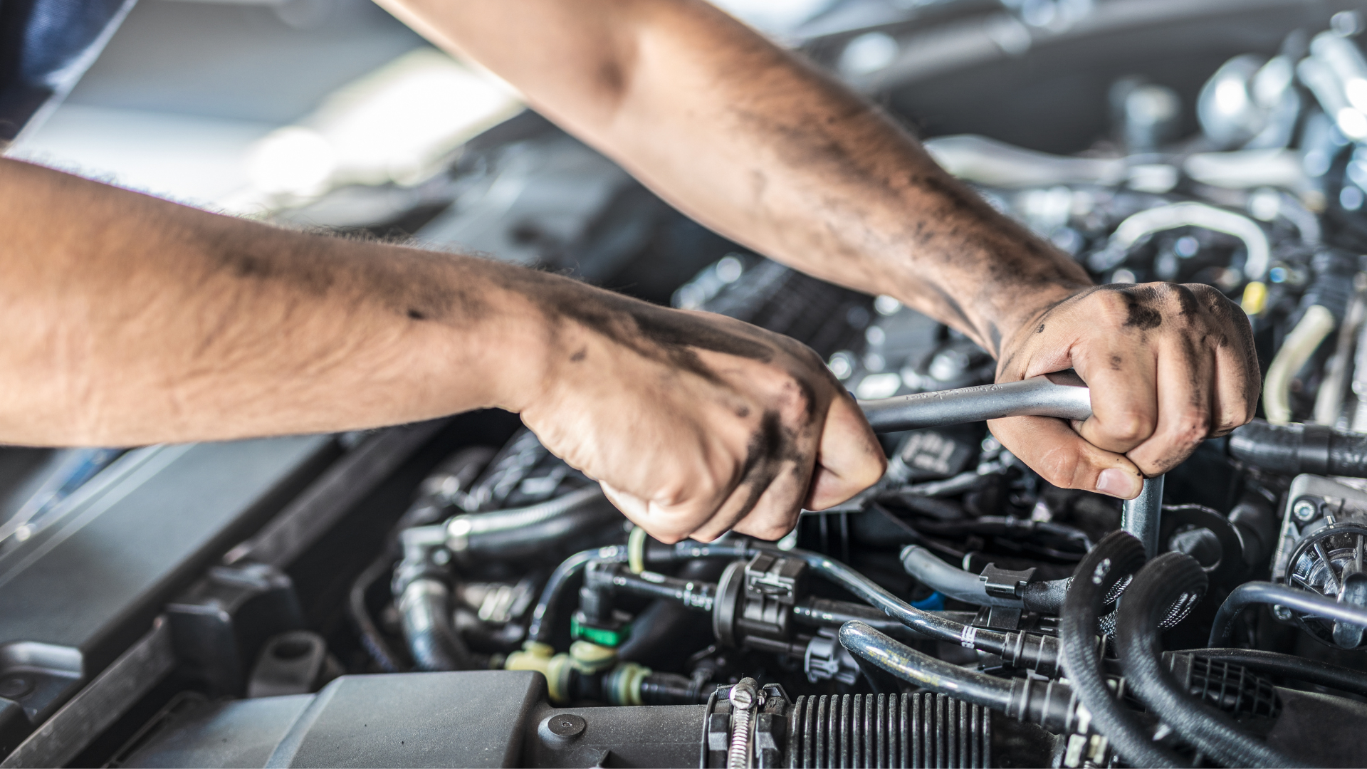 A man is working on a car engine with a wrench.