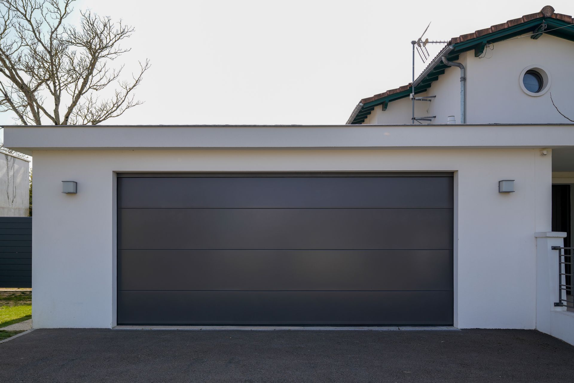 Gray garage door on a white building with gravel driveway.