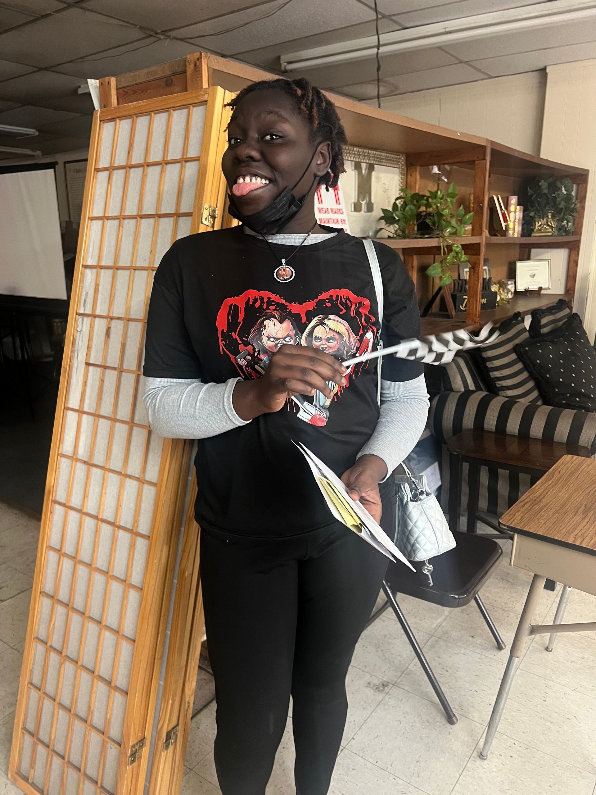 A woman wearing a black shirt with a heart on it is standing in a room.