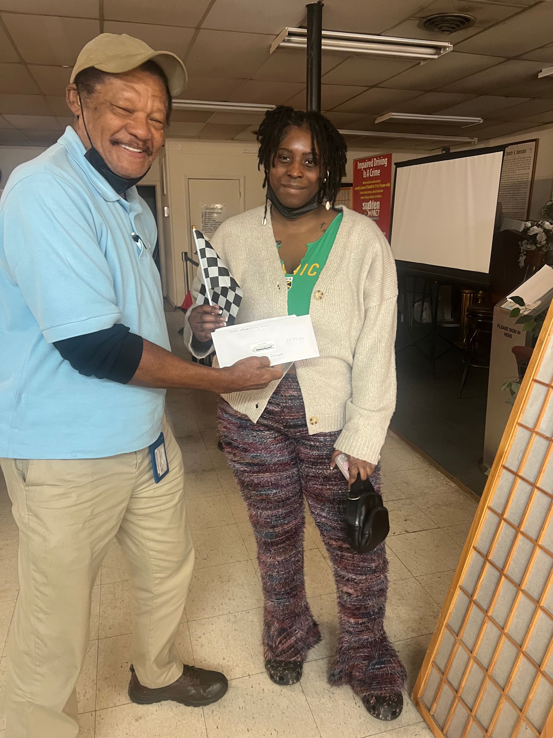 A man is giving a woman a check in a room.