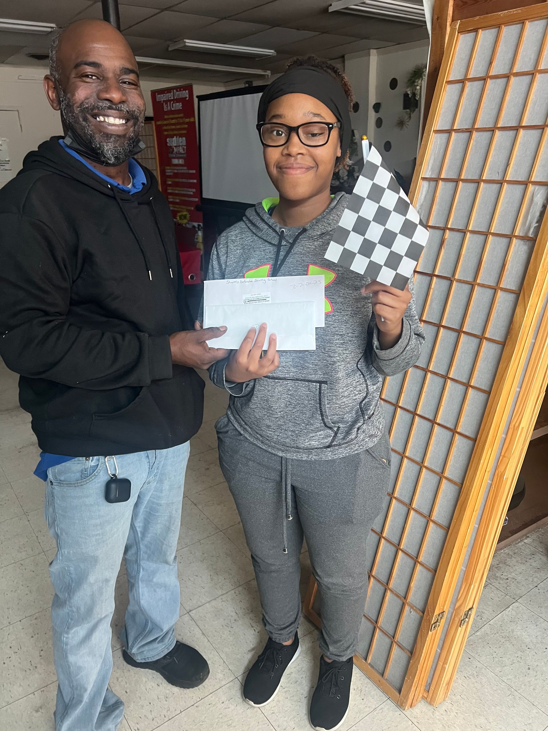 A man is giving a check to a boy who is holding a checkered flag.