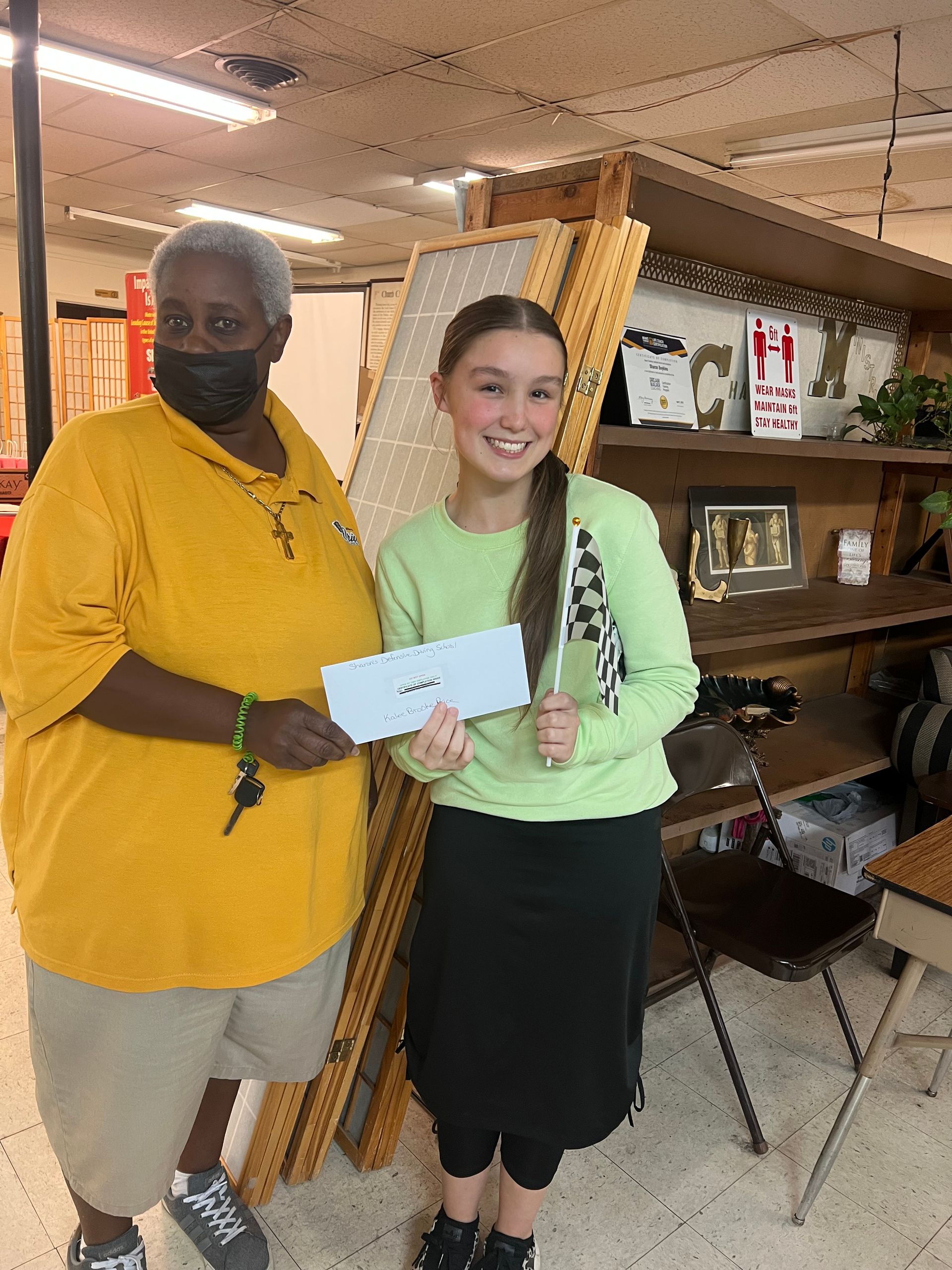 A man and a girl are standing next to each other holding a check.