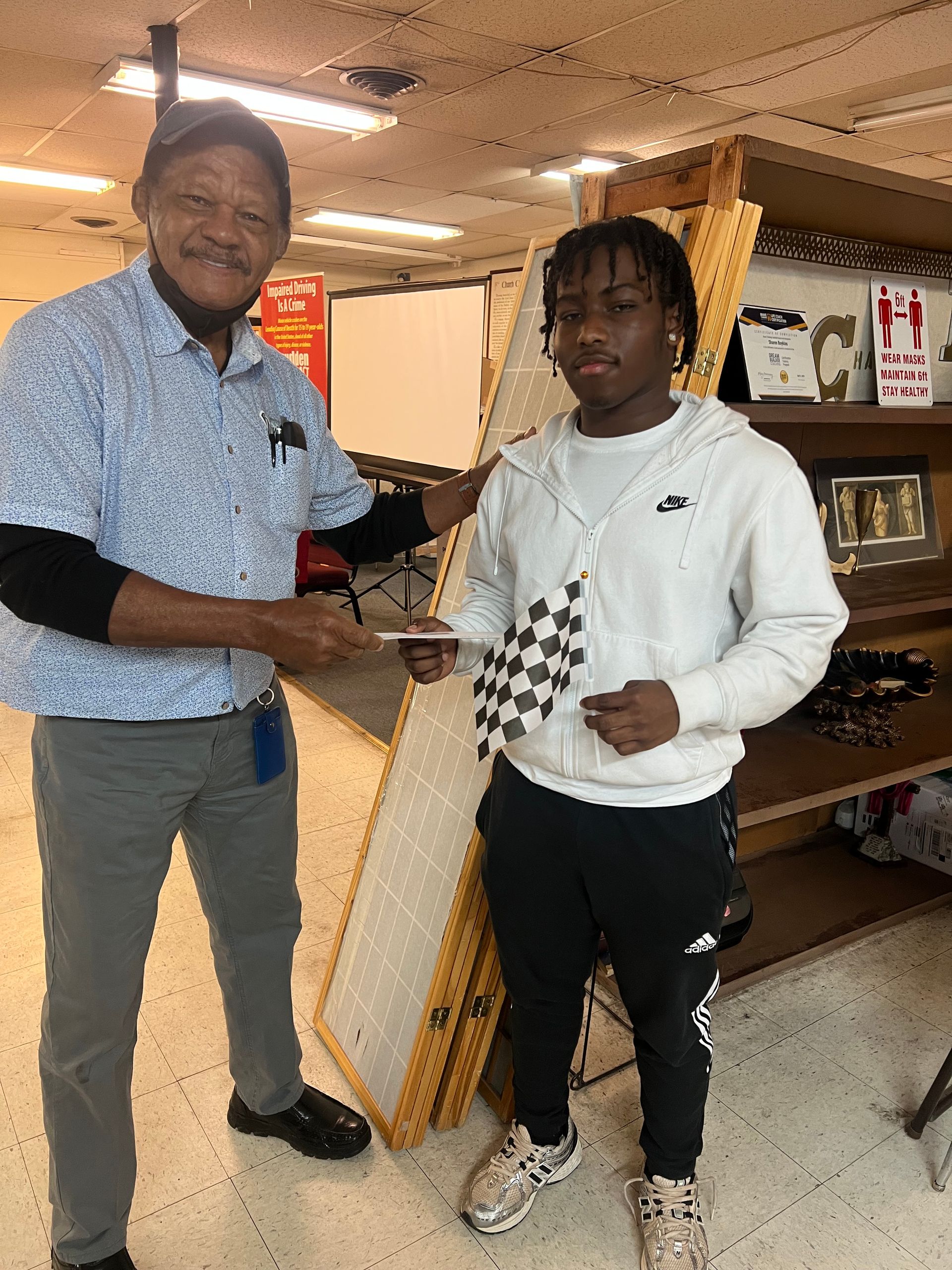 A man is giving a checkered flag to a young boy.