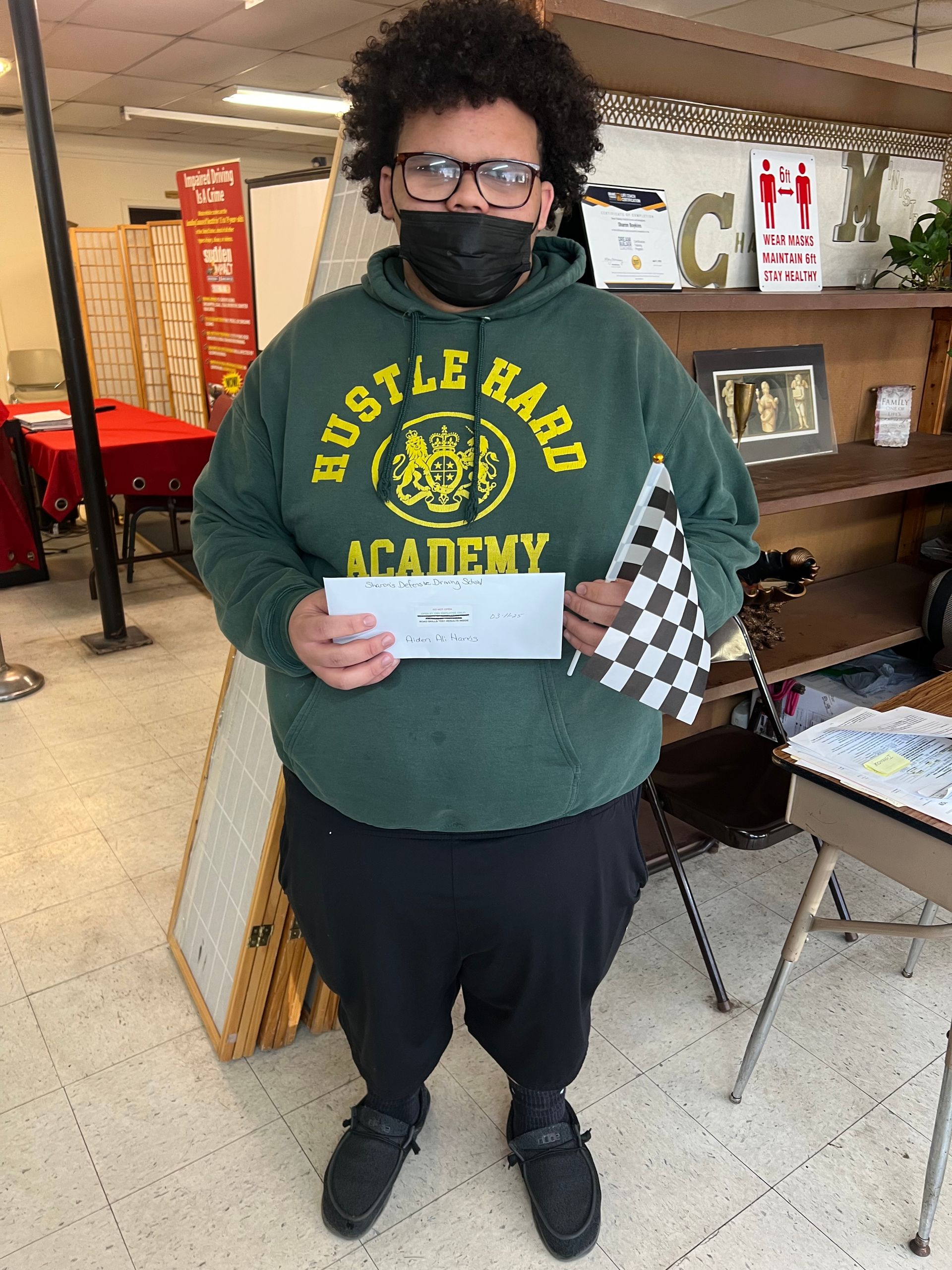 A man wearing a mask is holding a check and a checkered flag.