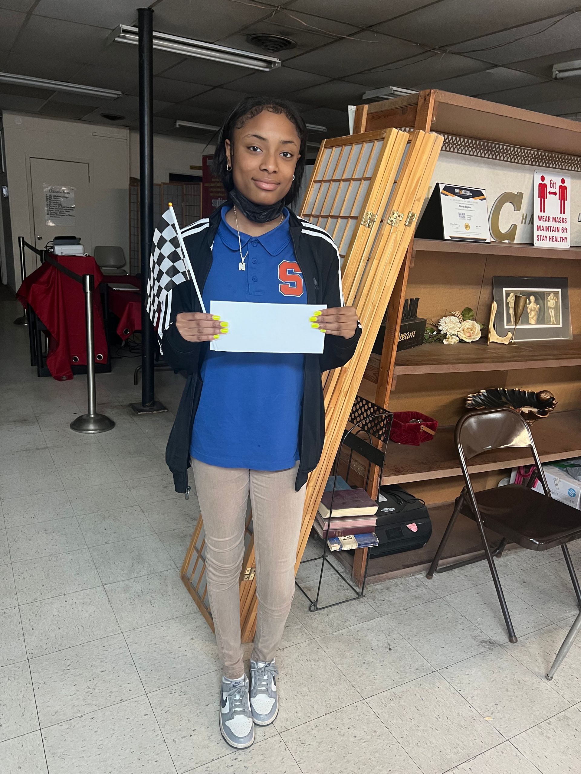 A young girl is standing in a room holding a piece of paper.