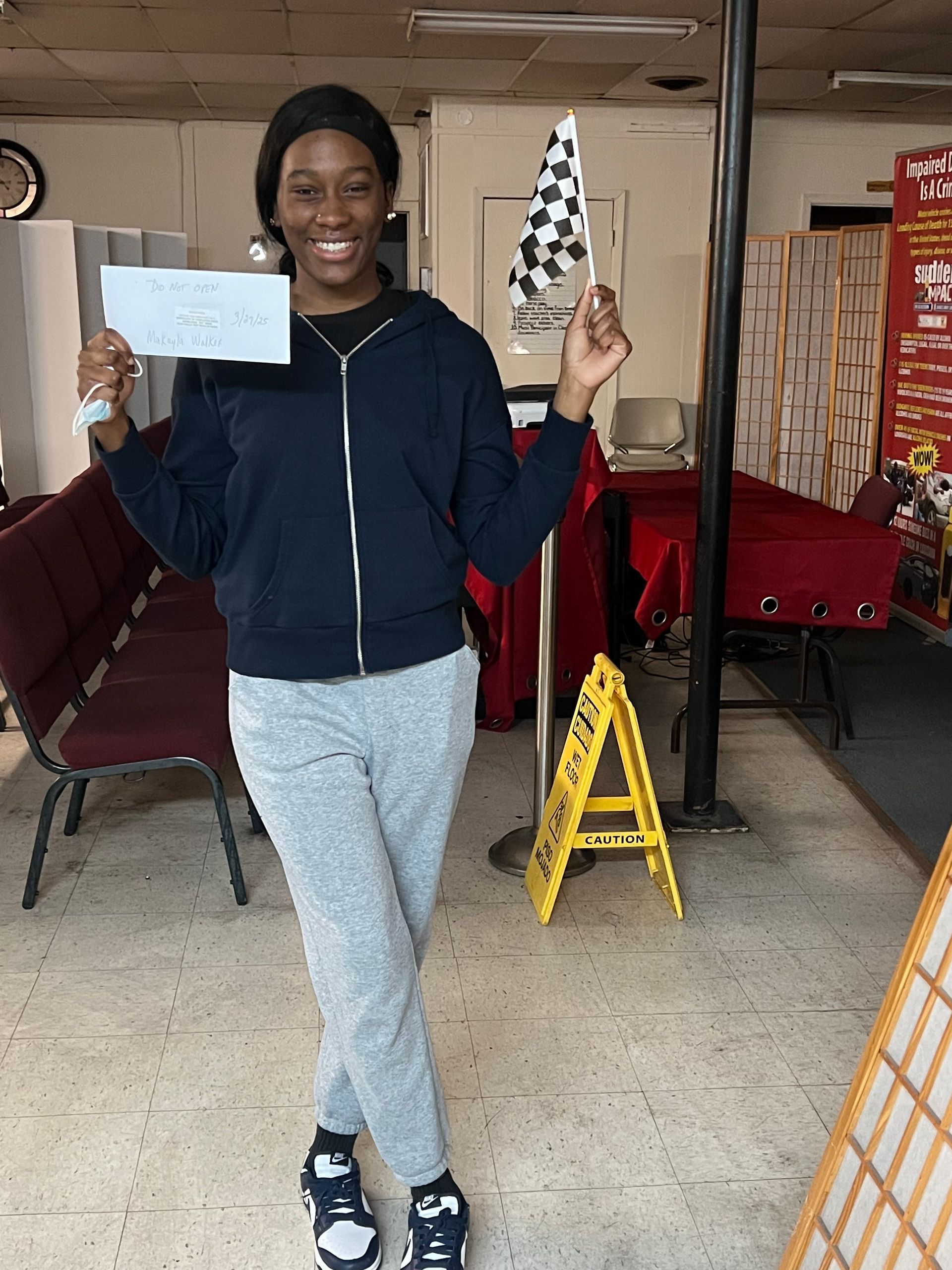 A woman holding a check in front of a yellow a sign