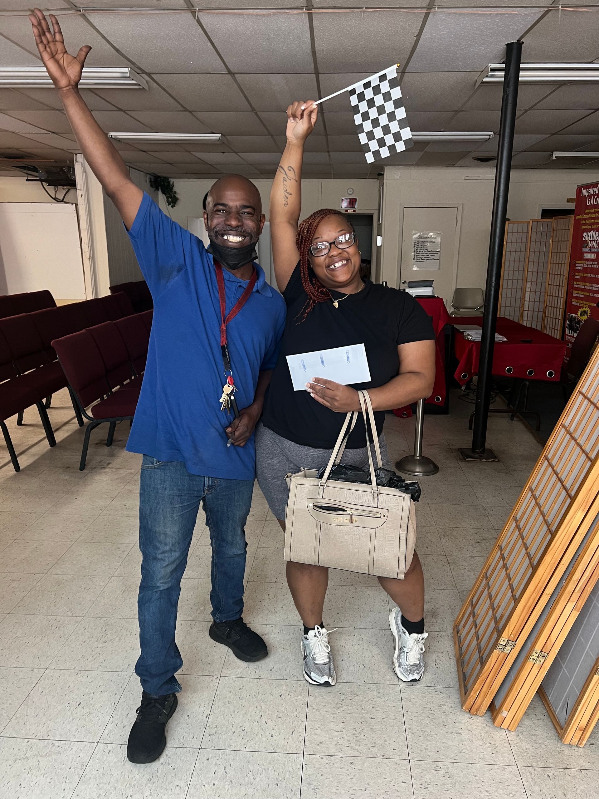 A man and a woman holding a checkered flag in a room