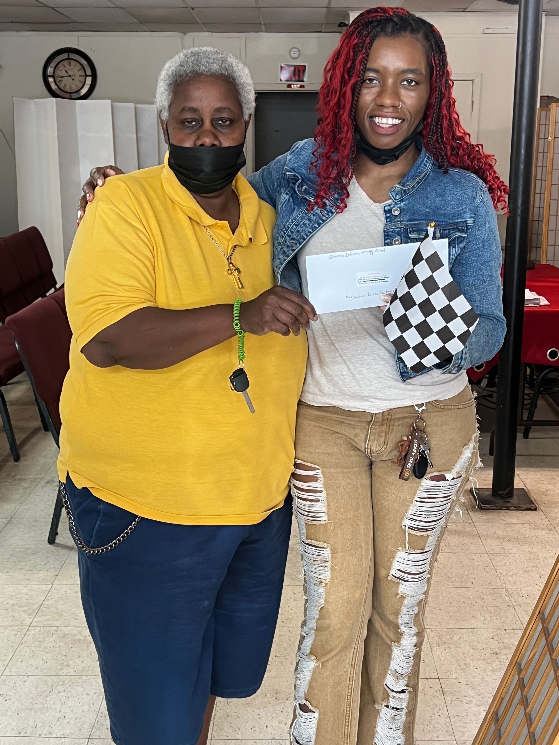 Two women wearing masks are standing next to each other in a room.