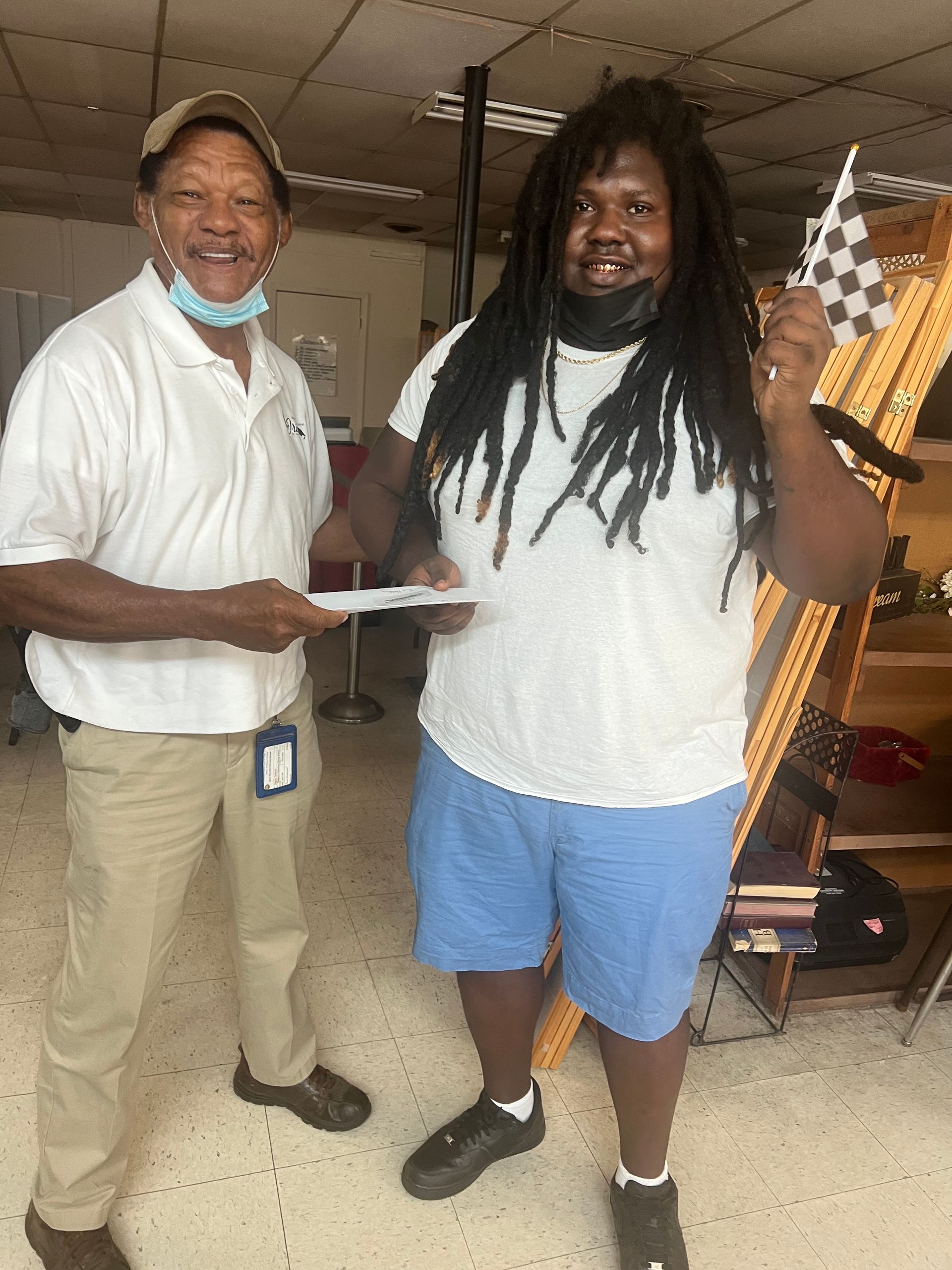 Two men are standing next to each other and one of them is holding a check.