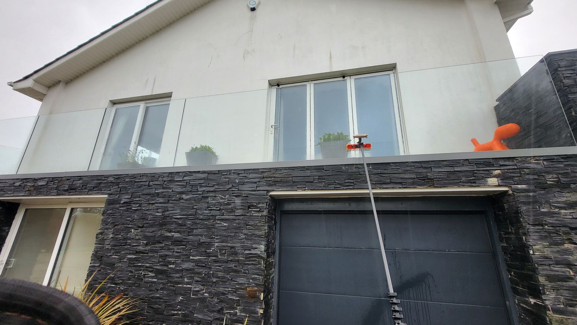 A man is cleaning the windows of a house with a hose.