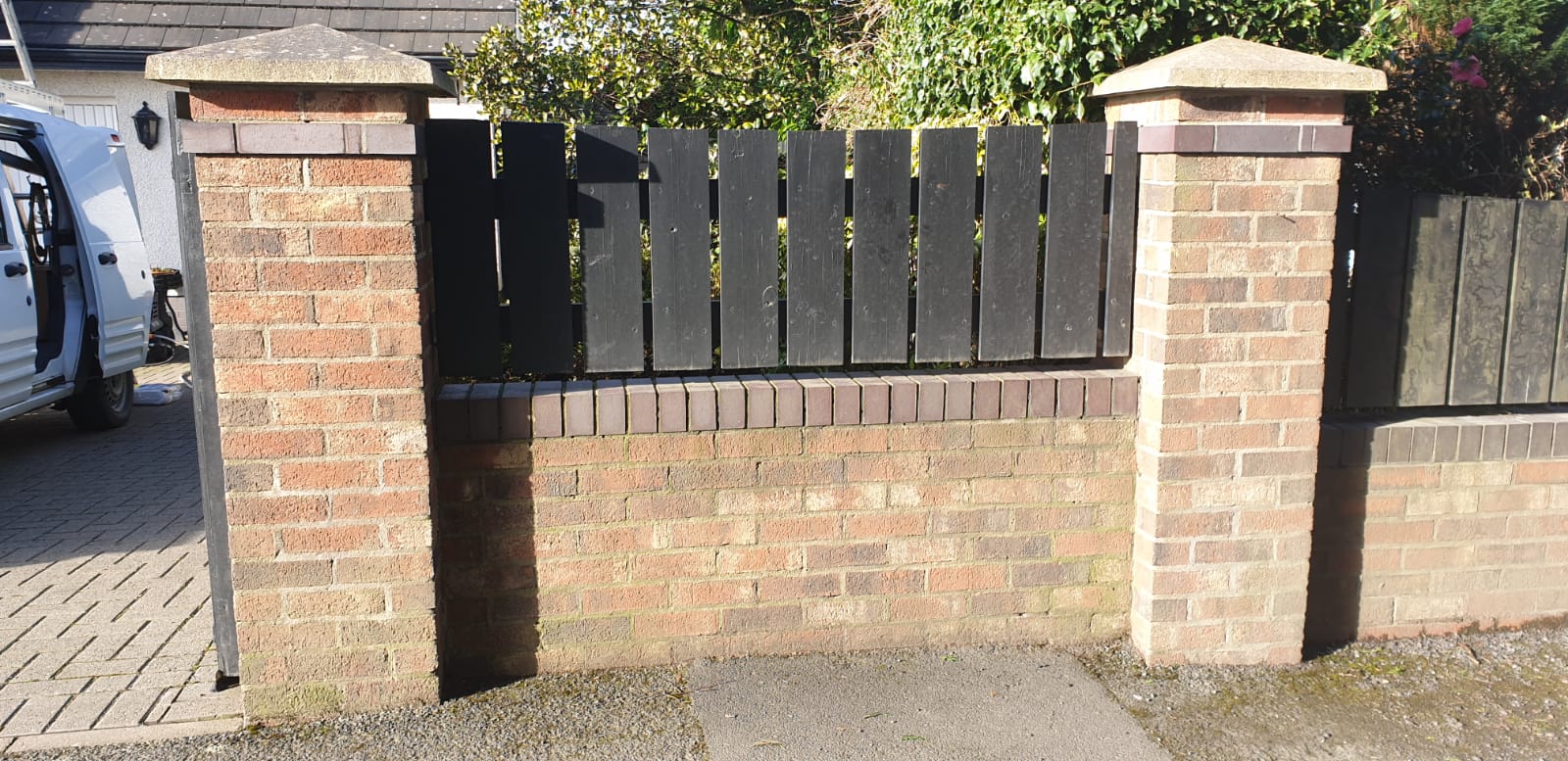 A brick wall with a wooden fence behind it