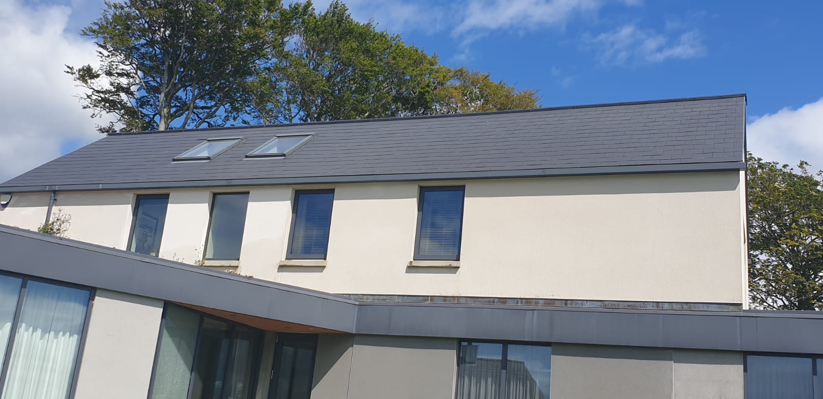 A white house with a black roof and a lot of windows.