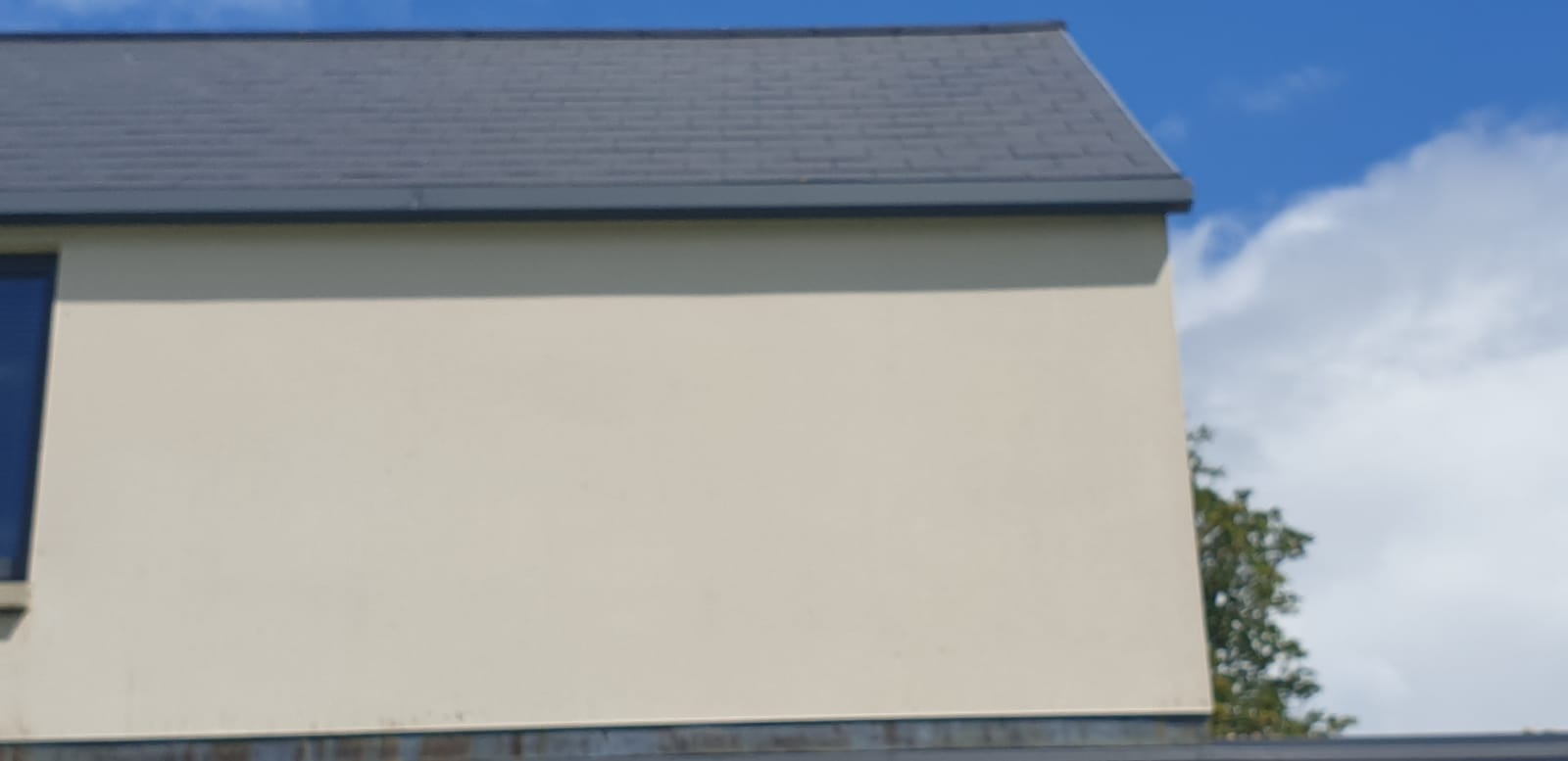A white house with a black roof and a blue sky in the background.