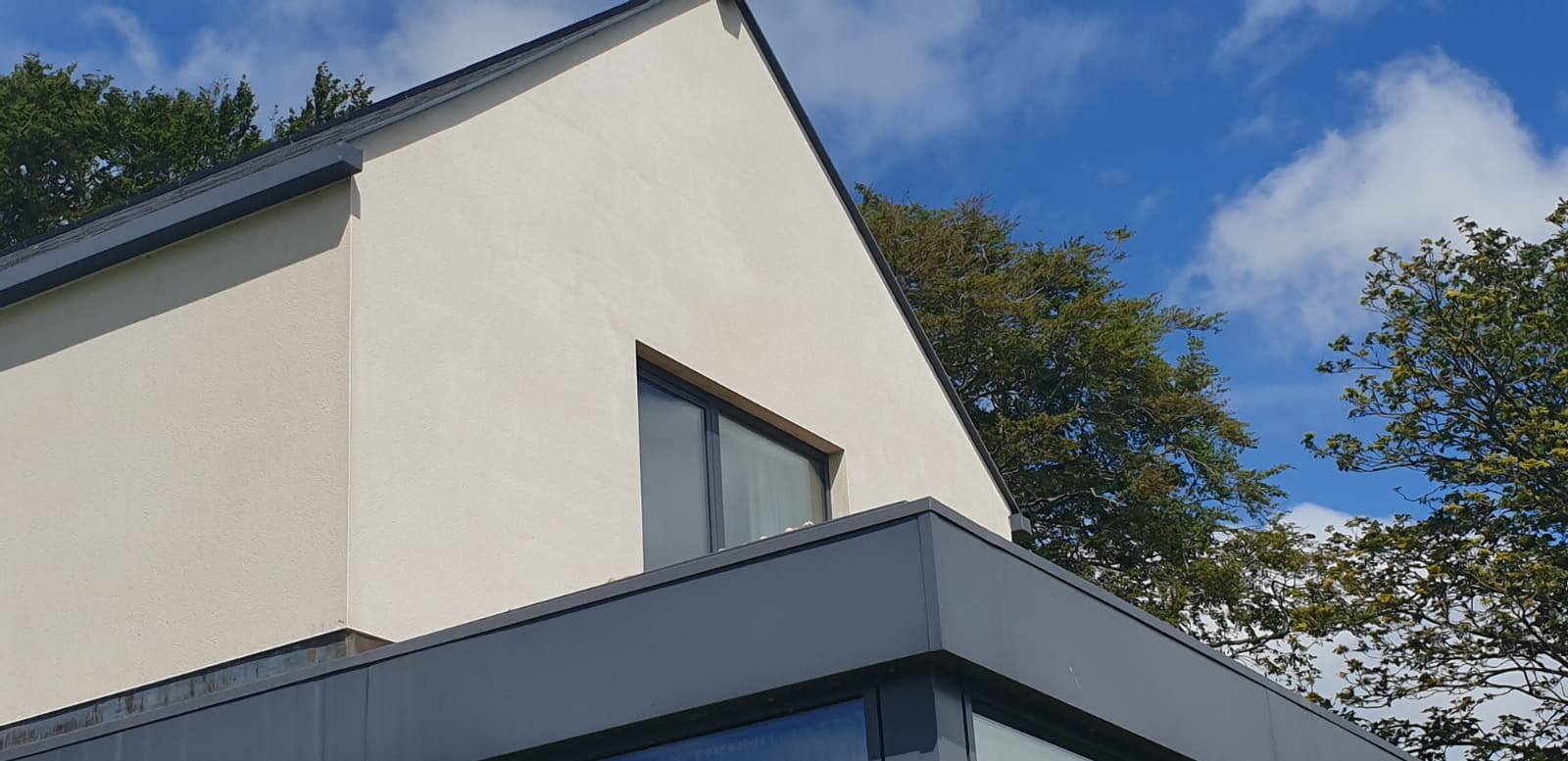 A white house with a blue sky in the background and trees in the foreground.