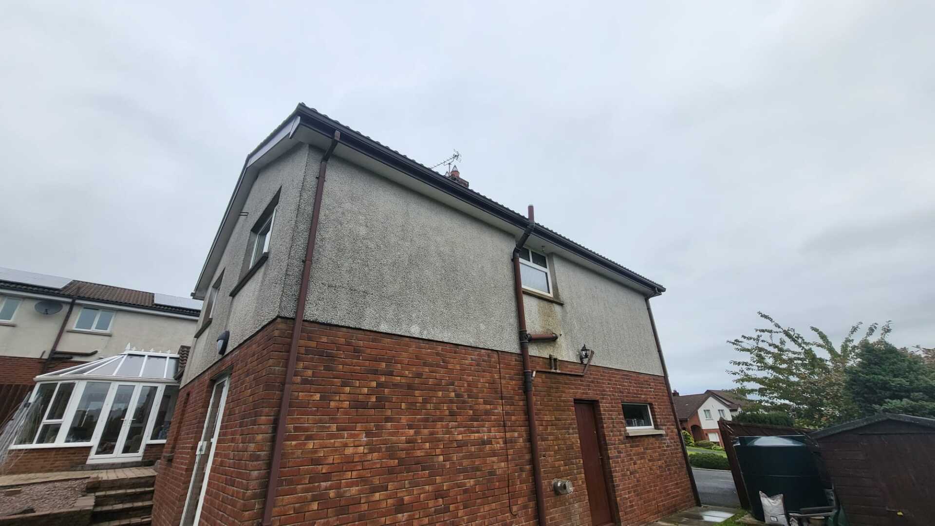 A brick house with a white roof and a drainpipe on the side of it.