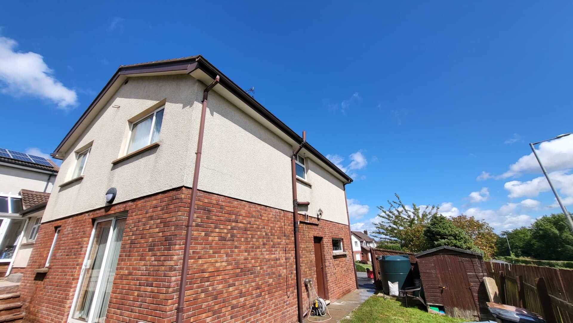A brick house with a shed in the backyard on a sunny day.