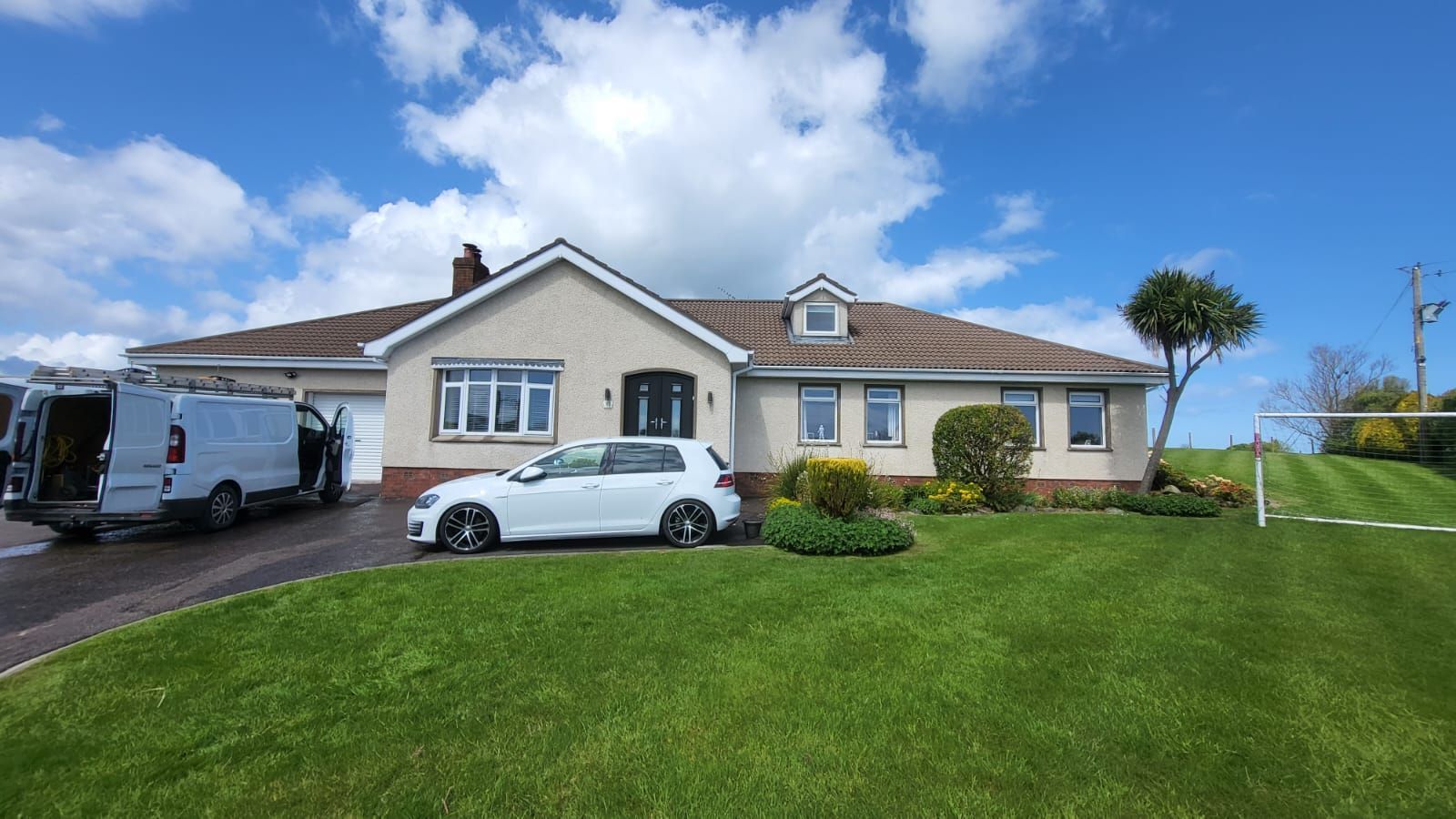 A white car is parked in front of a large house.