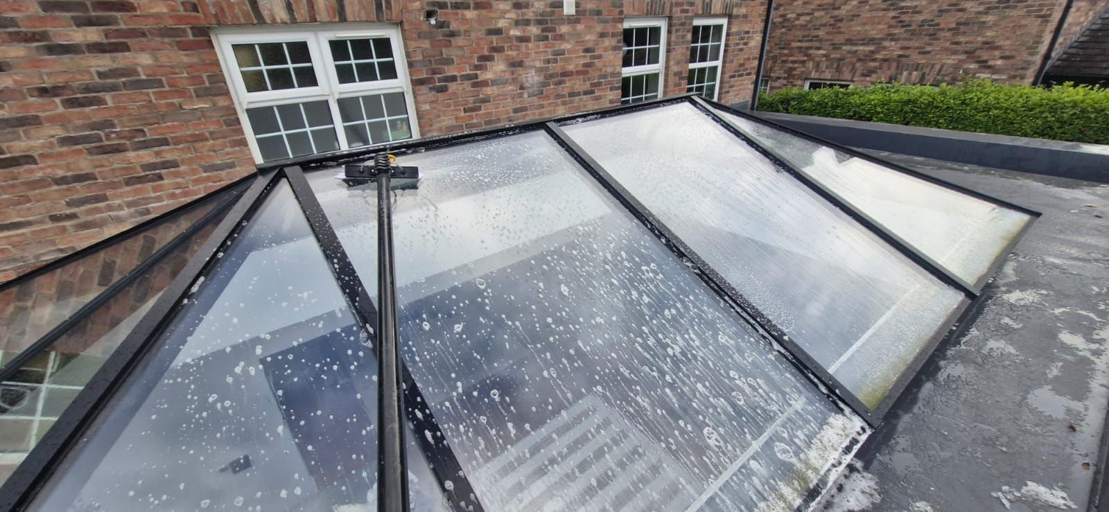 A roof with a glass roof and a brick building in the background.