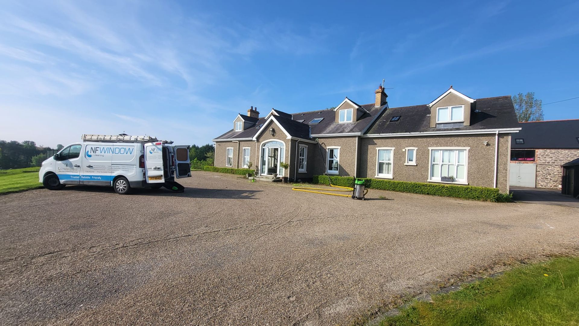 A white van is parked in front of a large house.