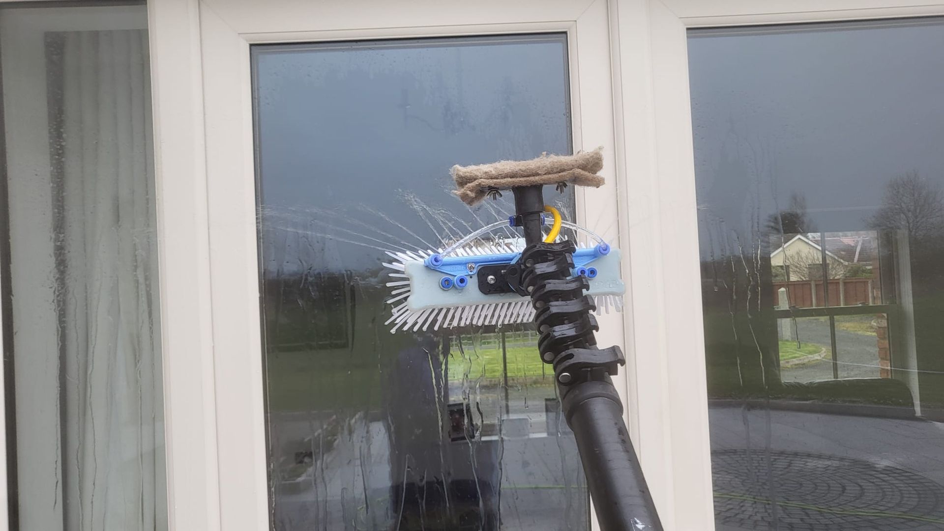 A person is cleaning a window with a brush.