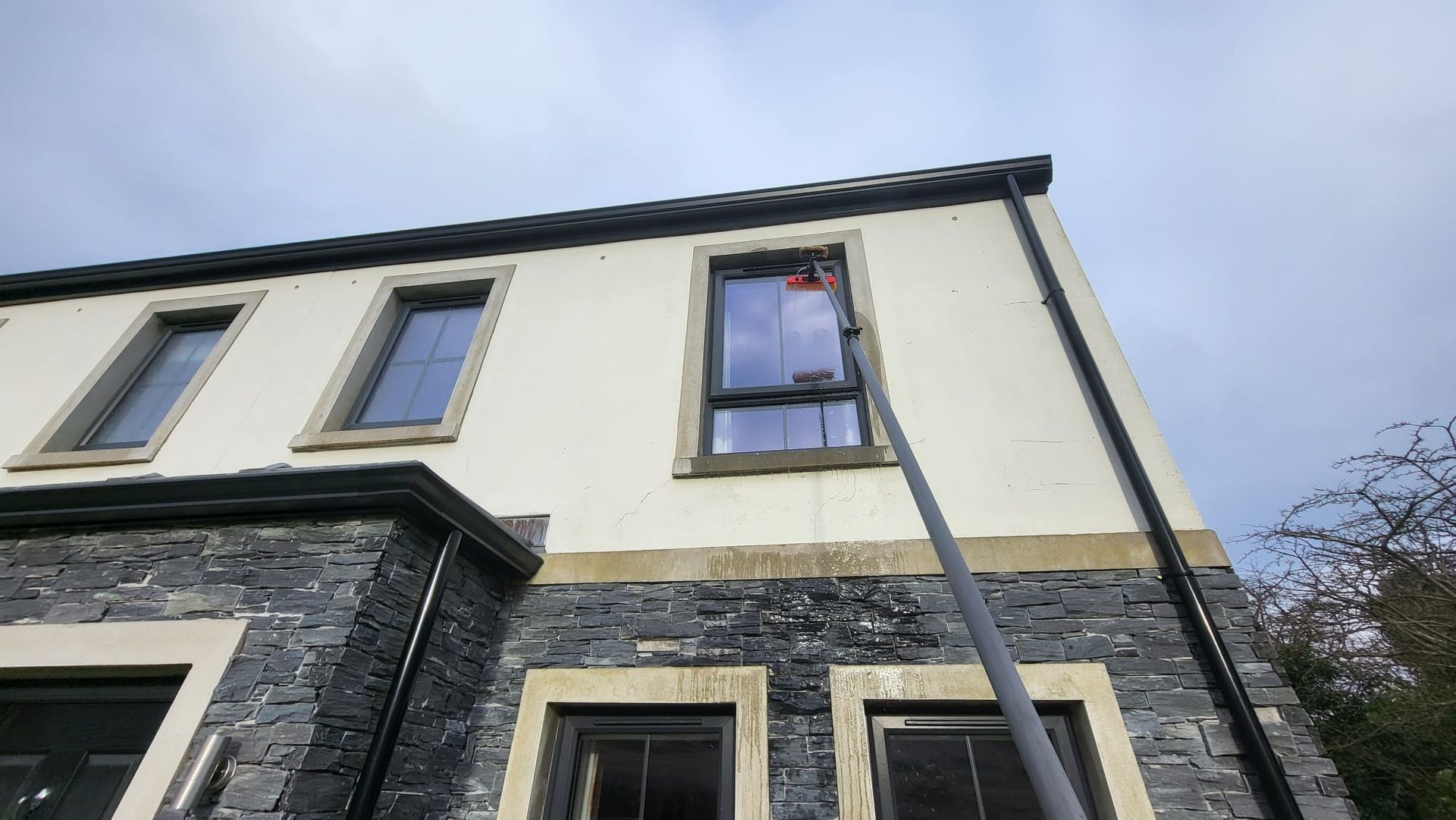 A person is cleaning the windows of a building with a hose.