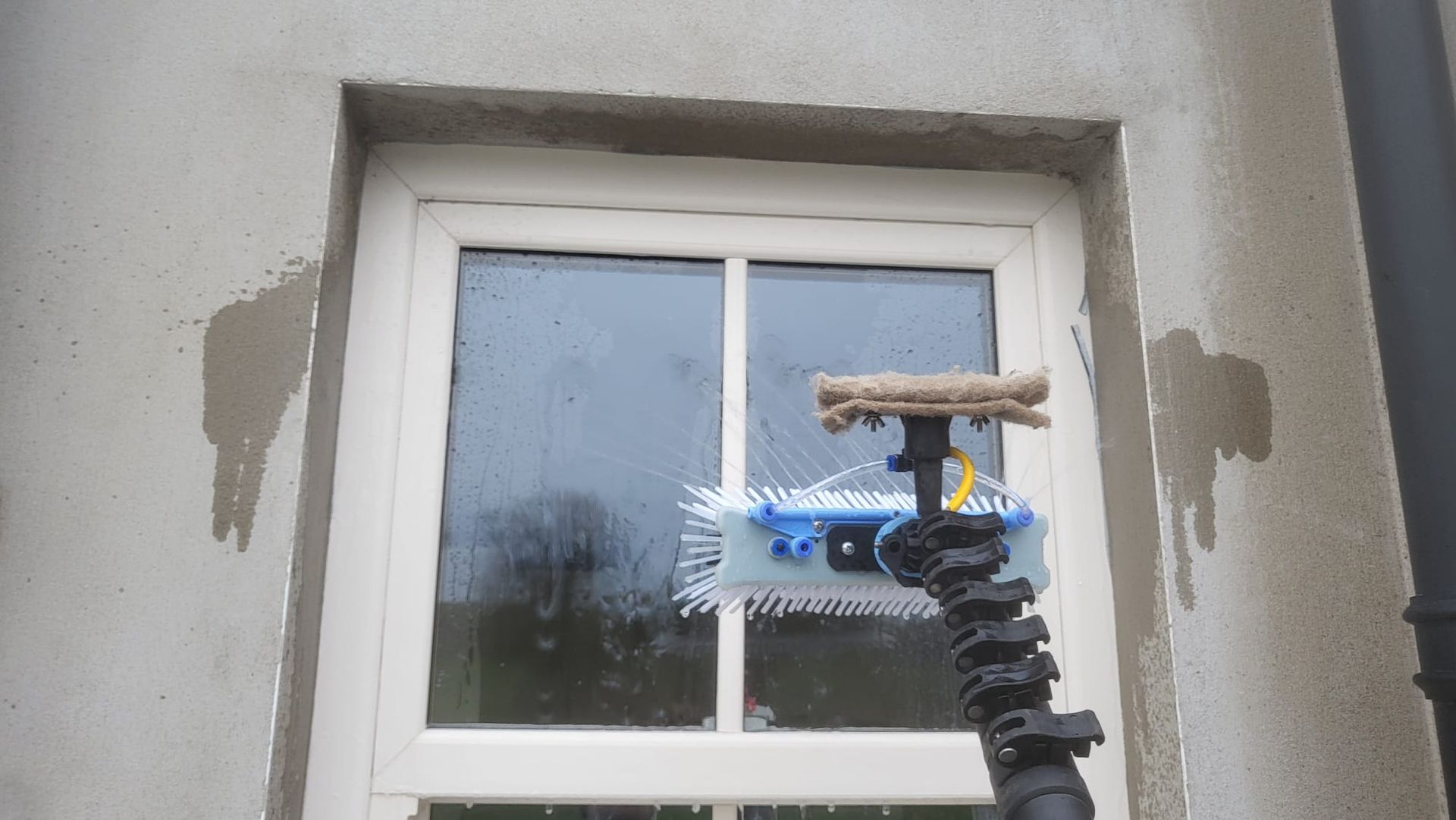 A person is cleaning a window with a hose.