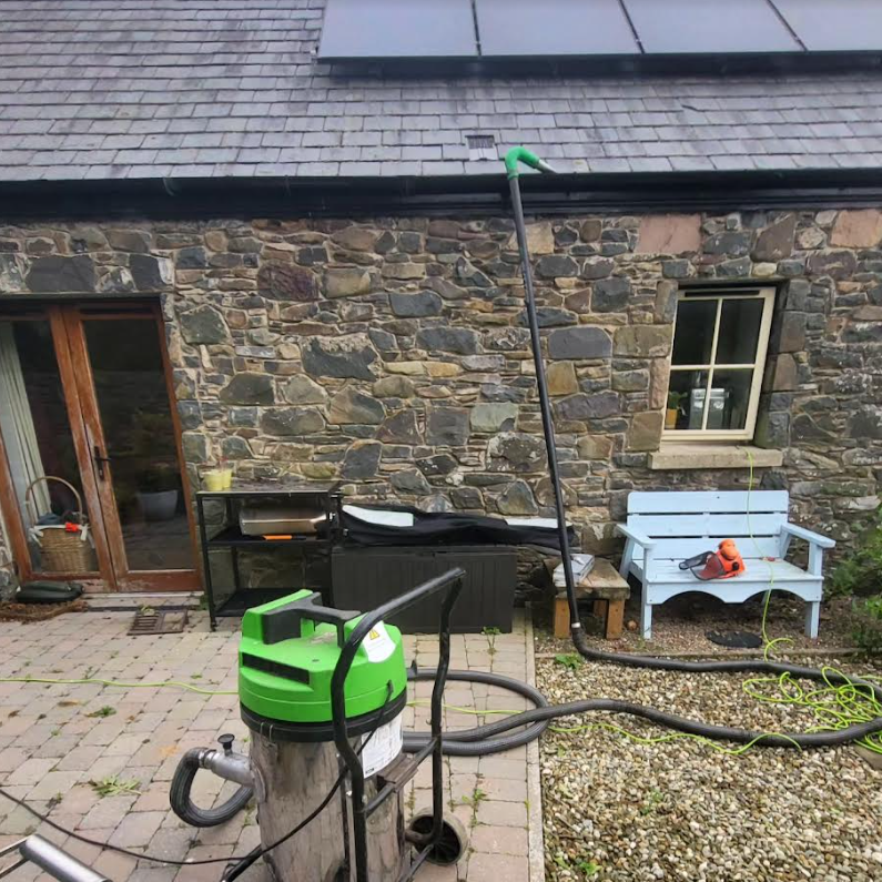 A green vacuum cleaner is sitting in front of a stone building.
