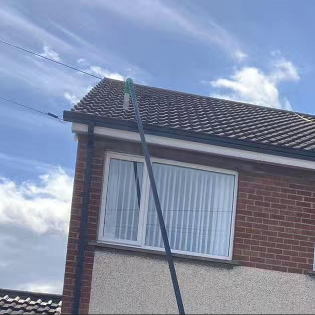 A brick house with a green pole hanging from the roof.
